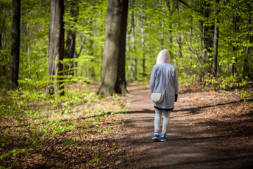 Young woman walking alone in early spring forest
