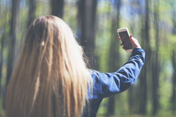 Woman taking selfie with mobile phone during walk in park