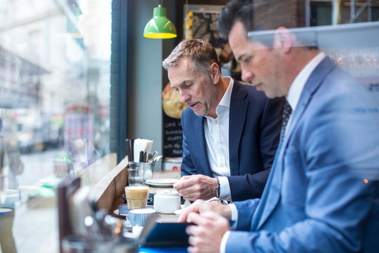 Two businessmen having working lunch in restaurant