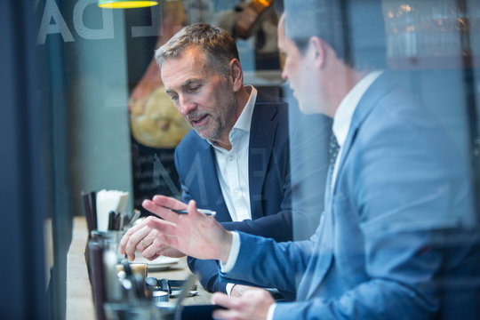 Two businessmen having discussion in restaurant window seat