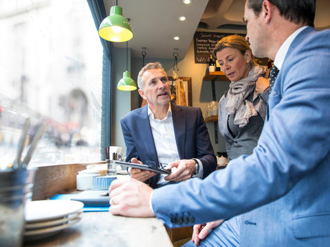 Businessmen and woman having discussion in restaurant window seat