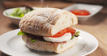 Fly out reveal ciabatta sandwich with speck, mazzarella and vegetables, 4k photo