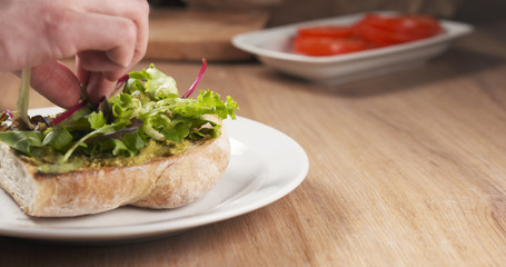 shot of salad leaves put on ciabatta bread preparing sandwich, 4k photo