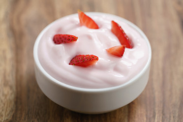 organic strawberry yogurt in white bowl on wood table, shallow focus