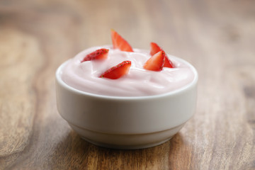 organic strawberry yogurt in white bowl on wood table, shallow focus