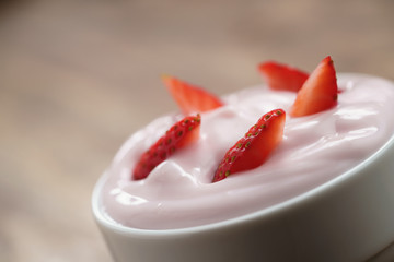 organic strawberry yogurt in white bowl on wood table, shallow focus