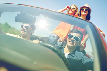 happy friends driving in cabriolet car