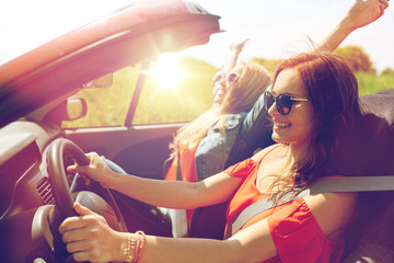smiling young women driving in cabriolet car