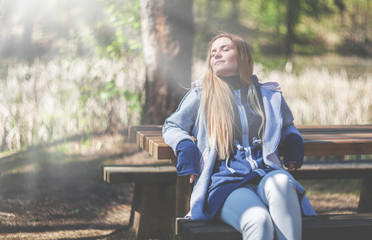 Woman enjoying sun sitting on bench in park