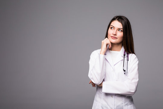 Thoughtful, Young female doctor looking away isolated on grey background