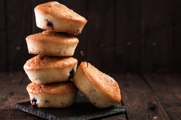 Blueberry muffins with fresh berries on old wooden background