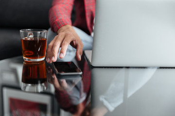 Cropped image of young man using laptop computer holding telephone.