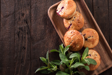 Blueberry muffins with fresh berries on old wooden background