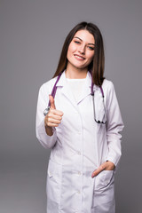 Female doctor with thumbs up gesture against grey background