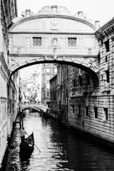Ponte dei sospiri with a gondola floating towards it. Venice, Italy. Black and white.