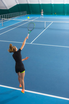 The young girl in a closed tennis court with ball