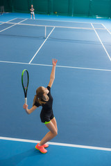 The young girl in a closed tennis court with ball