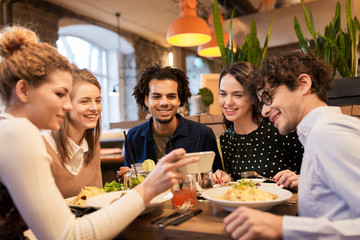 friends with smartphone eating at restaurant
