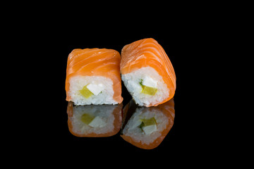 Rolls with daikon, salmon and cream cheese on a black background with reflection