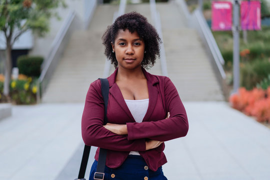 Portrait of young woman standing outdoors, arms folded