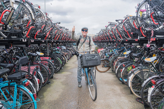 Cyclist on bicycle looking at camera giving thumbs up, Amsterdam, Netherlands