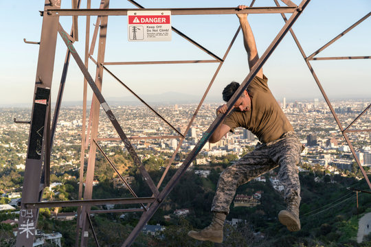 Soldier wearing combat clothing dangling from electricity pylon, Runyon Canyon, Los Angeles, California, USA