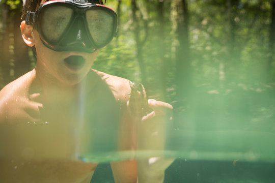 Teenage boy wearing snorkel holding common snapping turtle, Econfina Creek, Youngstown, Florida, USA