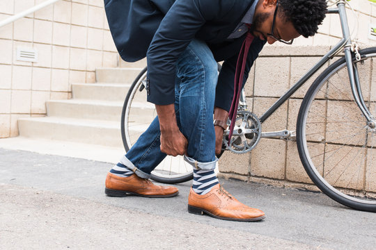Young male cyclist rolling down jeans on railway station platform