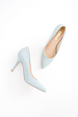 Beauty blog concept. Pale blue female shoes on white background. Flat lay, top view trendy fashion feminine background.