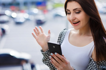 Young pretty stylish exulting woman reading message on smart phone