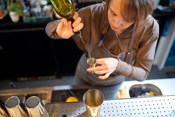bartender pouring alcohol into jigger at bar