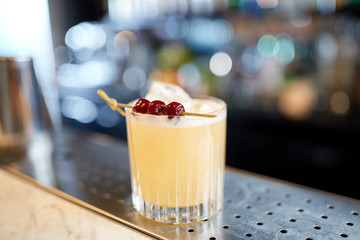 glass of cocktail with cherries at bar