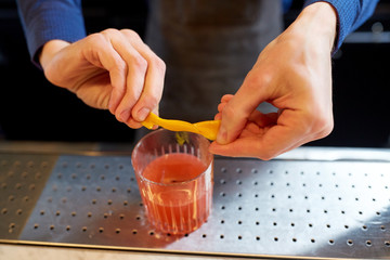 bartender with glass of cocktail and orange peel