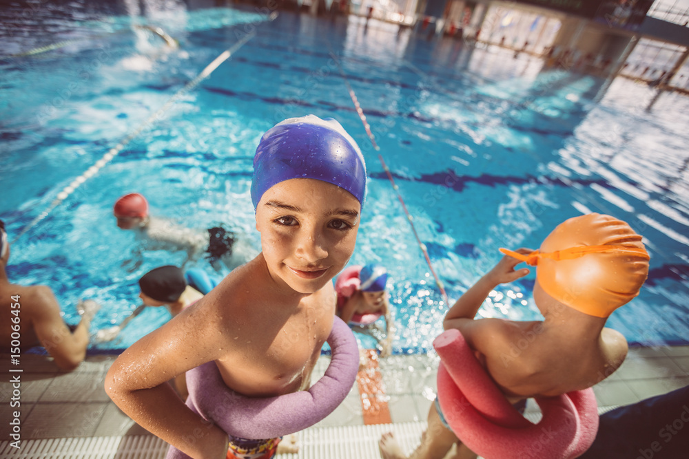 Wall mural happy children kids group at swimming pool class learning to swim