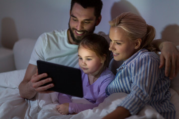 happy family with tablet pc in bed at home