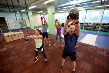 Fototapeta na wymiar group of people with kettlebells exercising in gym