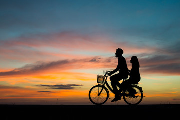  Silhouette couple and bycicle on sunset.