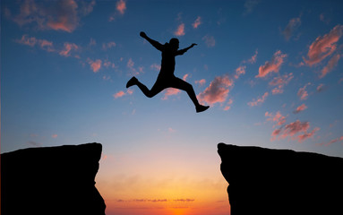 Man jumping across the gap from one rock to cling to the other. Man jumping over rocks with gap....