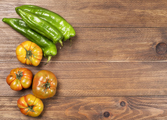 Tomatoes and peppers on wooden table.