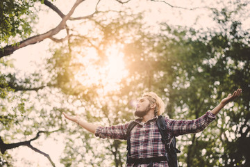 Young man sitting relax on tree in the forest.