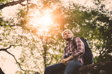 Young man sitting on tree in the forest.