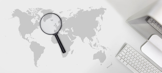searching concept, magnifying glass with international map on computer desk