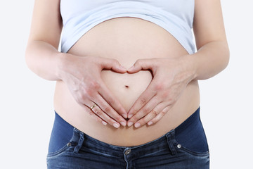 Pregnant woman holding hands in heart shape on belly, isolated on white background