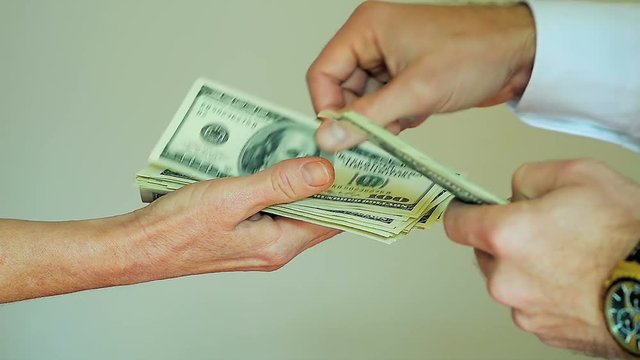 Close-Up of Paying Cash from Man Hands Counting out 100 Dollar Bills into a Woman Hand