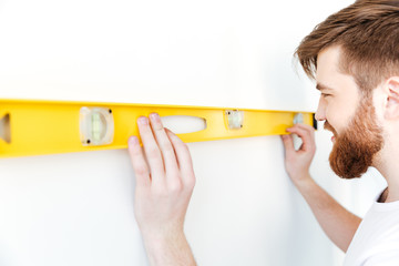 Young man standing indoors in new flat and make repair.