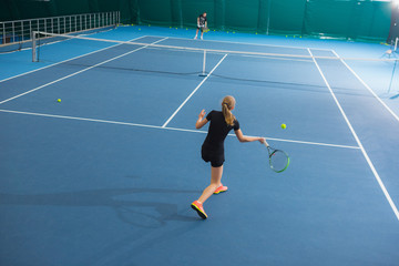 The young girl in a closed tennis court with ball