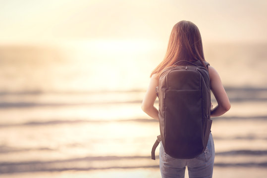 Traveling woman with backpack, Female looking at tropical beach and sea sunset