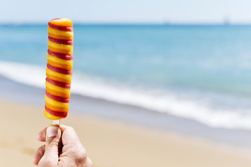 man eating a popsicle on the beach