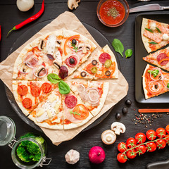 Pizza with ingredients, spices, oil and vegetables on black background. Flat lay, top view. Tasty italian food