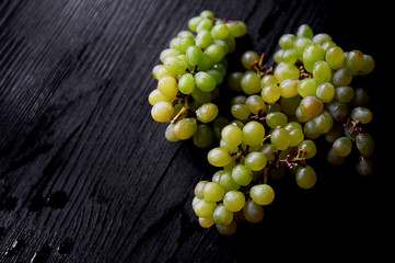 Beautiful fresh bunch of grapes on a dark wooden background. The droplets of water.Healthy eating